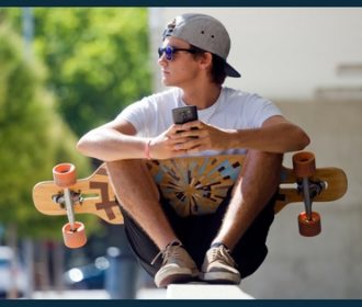 teenager holding a phone and a skateboard