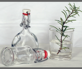 decorative bottles, a glass, a sprig of rosemary