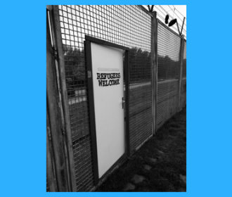 Fence with door that says Refugees Welcome