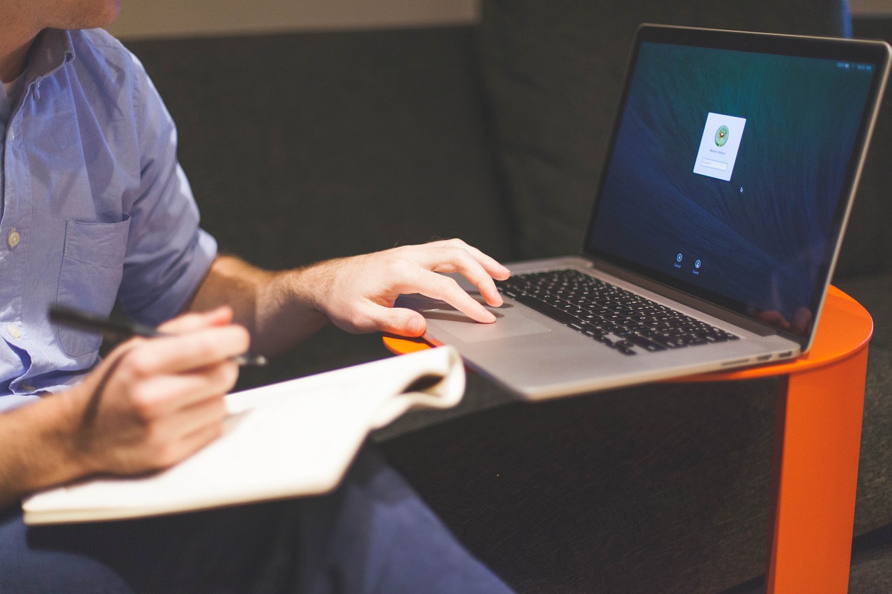 Man with notebook and hand on a laptop