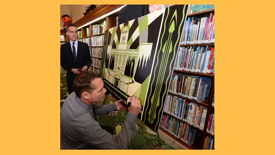 Los Angeles Mayor Eric Garcetti (left) watches artist Shepard Fairey sign a replica of LA’s first artist-designed, limited-edition library card at the press launch on April 19 at the Central Library. The card is available at all 73 locations of the Los Angeles Public Library.