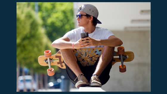 teenager holding a phone and a skateboard