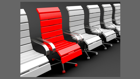 a row of white office chairs with one red chair