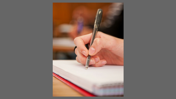 photograph of a hand writing in a notebook