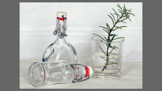 decorative bottles, a glass, a sprig of rosemary