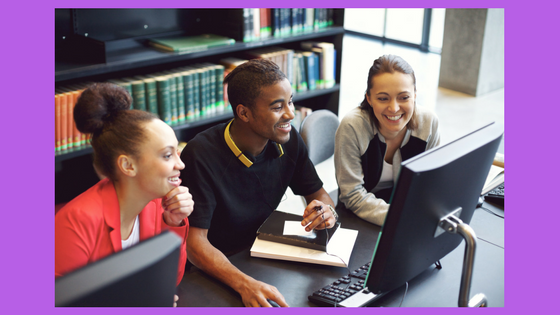 three people gathered around a computer at the library