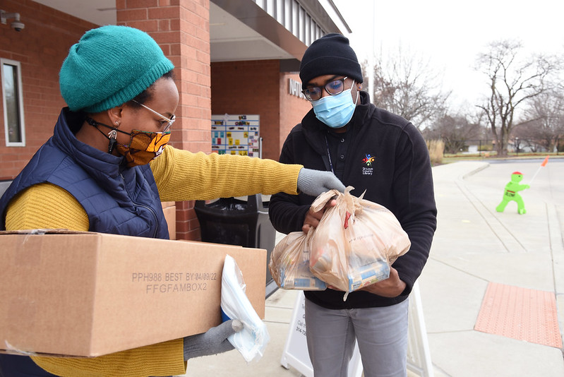 Photograph of people receiving food bags and boxes.