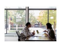 two people talking across a table, one is in military uniform