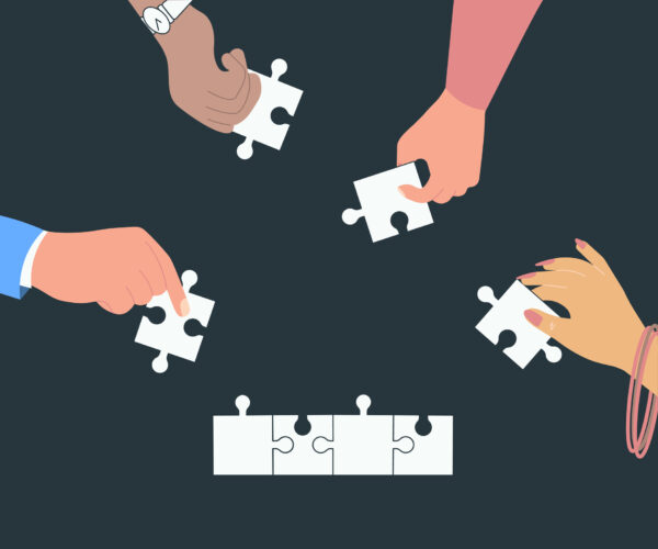 four hands assembling a white jigsaw puzzle each holding one piece