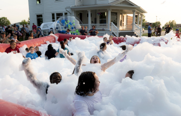 Kids frolic in a foam party in front of the library.