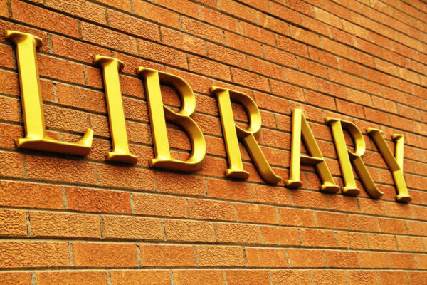 Gold letters spelling out LIBRARY on a red brick wall