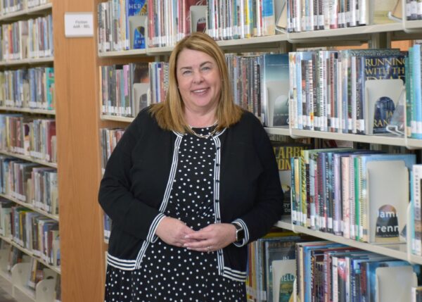 library director julie wendorf leaning against a library book shelf