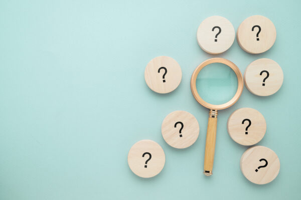 magnifying glass surrounded by round tiles with black question marks on them