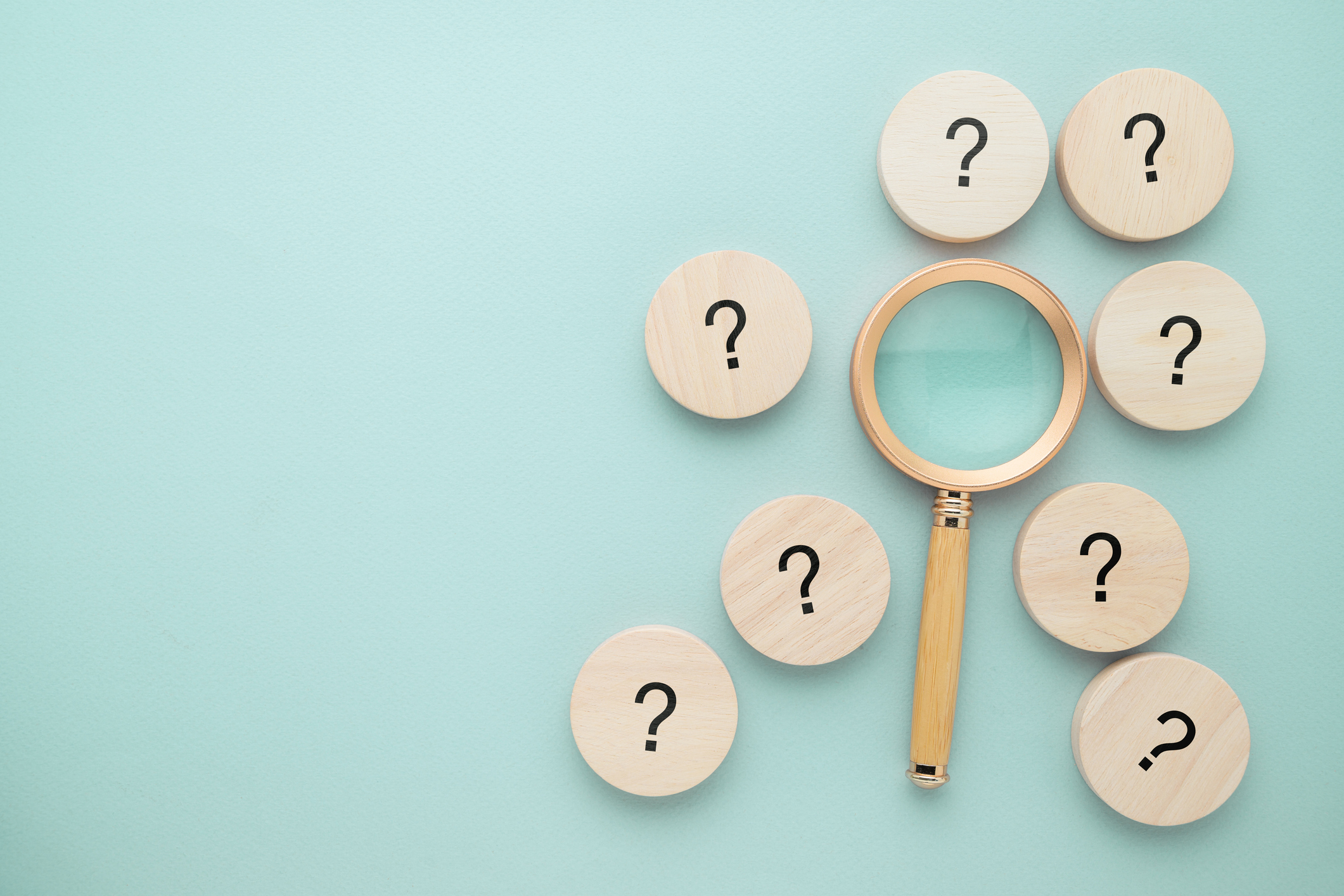 magnifying glass surrounded by round tiles with black question marks on them