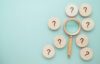 magnifying glass surrounded by round tiles with black question marks on them